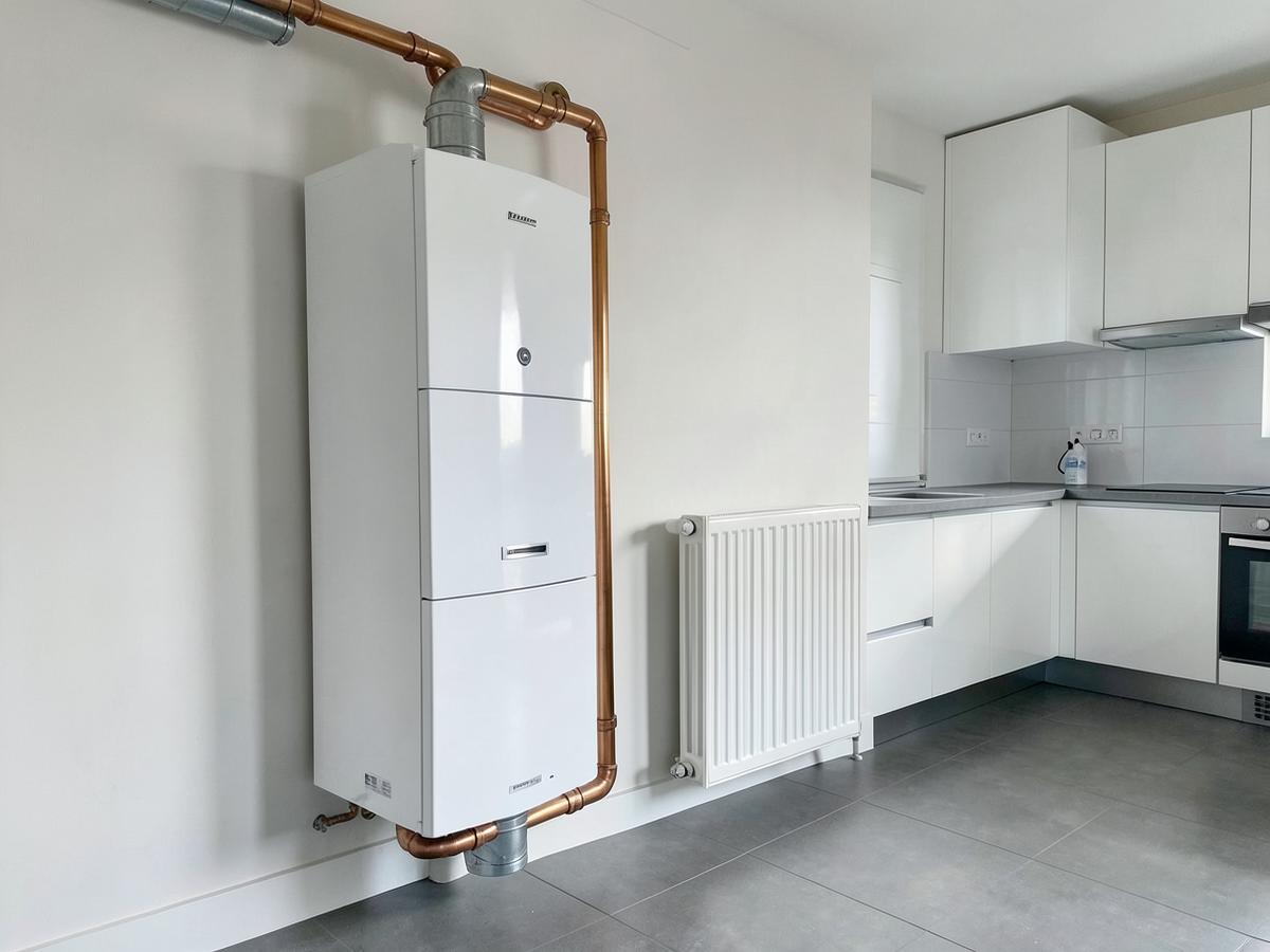 New wall mounted boiler with tidy copper pipework and a modern radiator