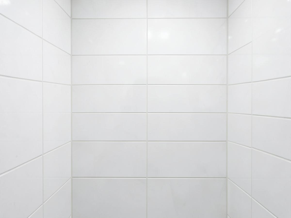 Freshly tiled white bathroom wall with straight, clean grout lines